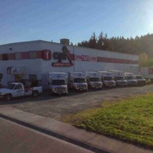 Multiple white CPI plumbing and heating service vans parked in front of commercial building with red and white signage.