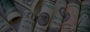 Rolled US currency bills displaying Federal Reserve seals, serial numbers including 17809, 10628, and 24224, with visible text stating legal tender.