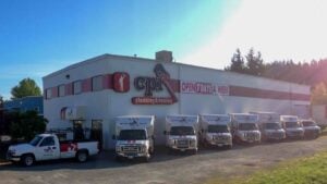CPI plumbing and heating company building with fleet of white service vans parked outside during Open 7 Days A Week promotion.