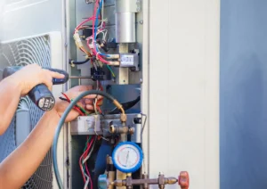 HVAC technician using digital multimeter to test air conditioning system internal components and refrigerant gauge.